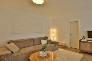 Ein Wohnzimmer mit einer Couch, einem Couchtisch, einem Fernseher und einer Tür.
