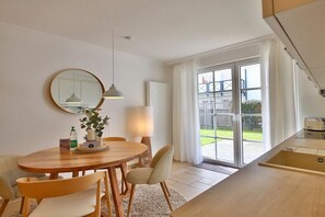 Eine moderne Küche mit Essbereich, großen Fenstern und Blick ins Freie.