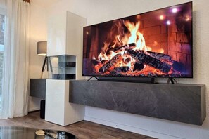 Un televisor de pantalla plana fixat a la paret sobre un moble modern d'entreteniment amb una estant de vidre.