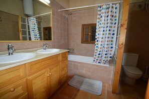 Ein Badezimmer mit zwei Waschbecken, einer Badewanne, einer Duschkabine und einem Holzkosmetikschrank.