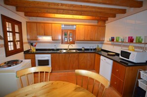 Eine Küche mit Holzausstattung, einem Spülbecken, einer Mikrowelle und einem Essbereich mit Holztisch und Stühlen.
