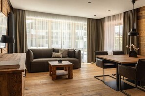 A modern living room with a sofa, coffee table, dining table, and chairs. - Holiday apartment in Reit im Winkl with Wi-Fi (Reit im Winkl)