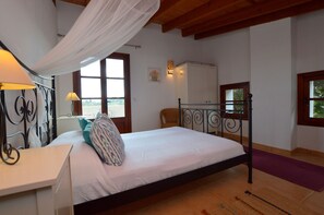 Ein Schlafzimmer mit Bett, Nachttisch, Lampe und Blick durch ein Fenster.