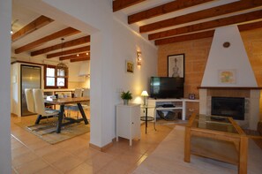 Ein modernes Wohnzimmer mit Kamin, Fernseher und Essbereich mit Stühlen und Tisch.