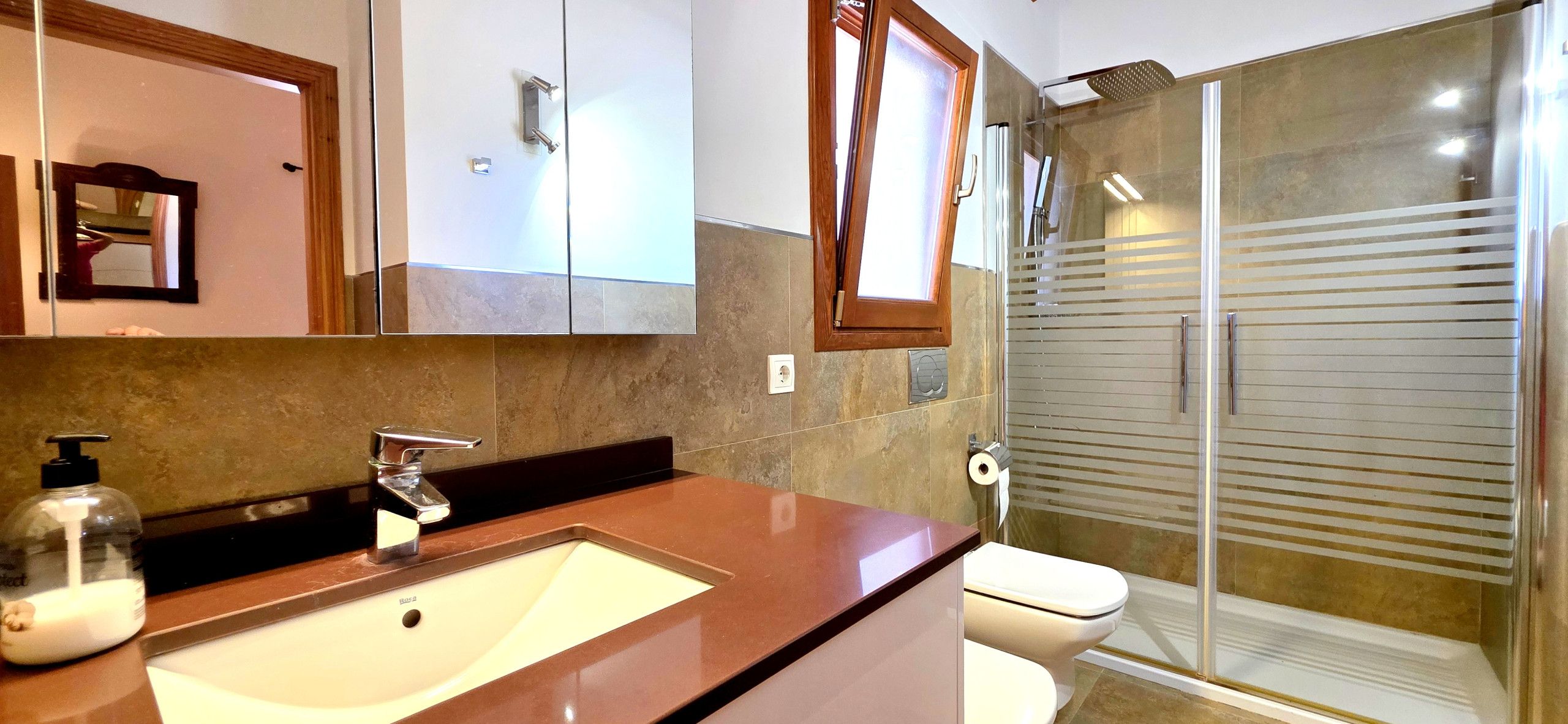 A bathroom with a sink, mirror, and shower.