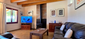 Una sala de estar con televisor, muebles de madera, chimenea y obras de arte en las paredes.
