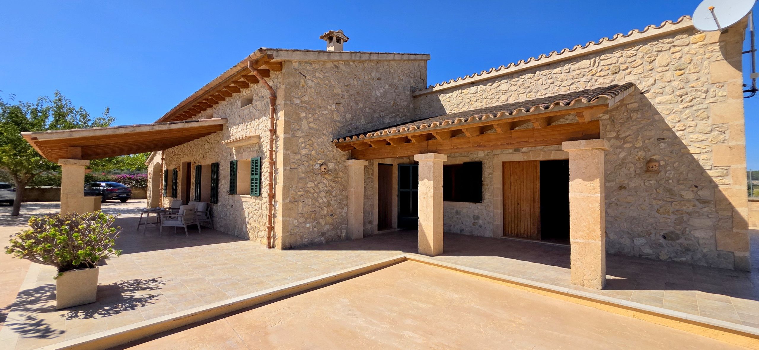 A stone building with a covered patio, outdoor seating, and a satellite dish.