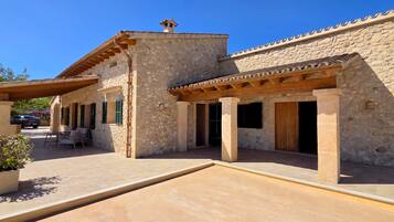 A stone building with a covered patio, outdoor seating, and a satellite dish.