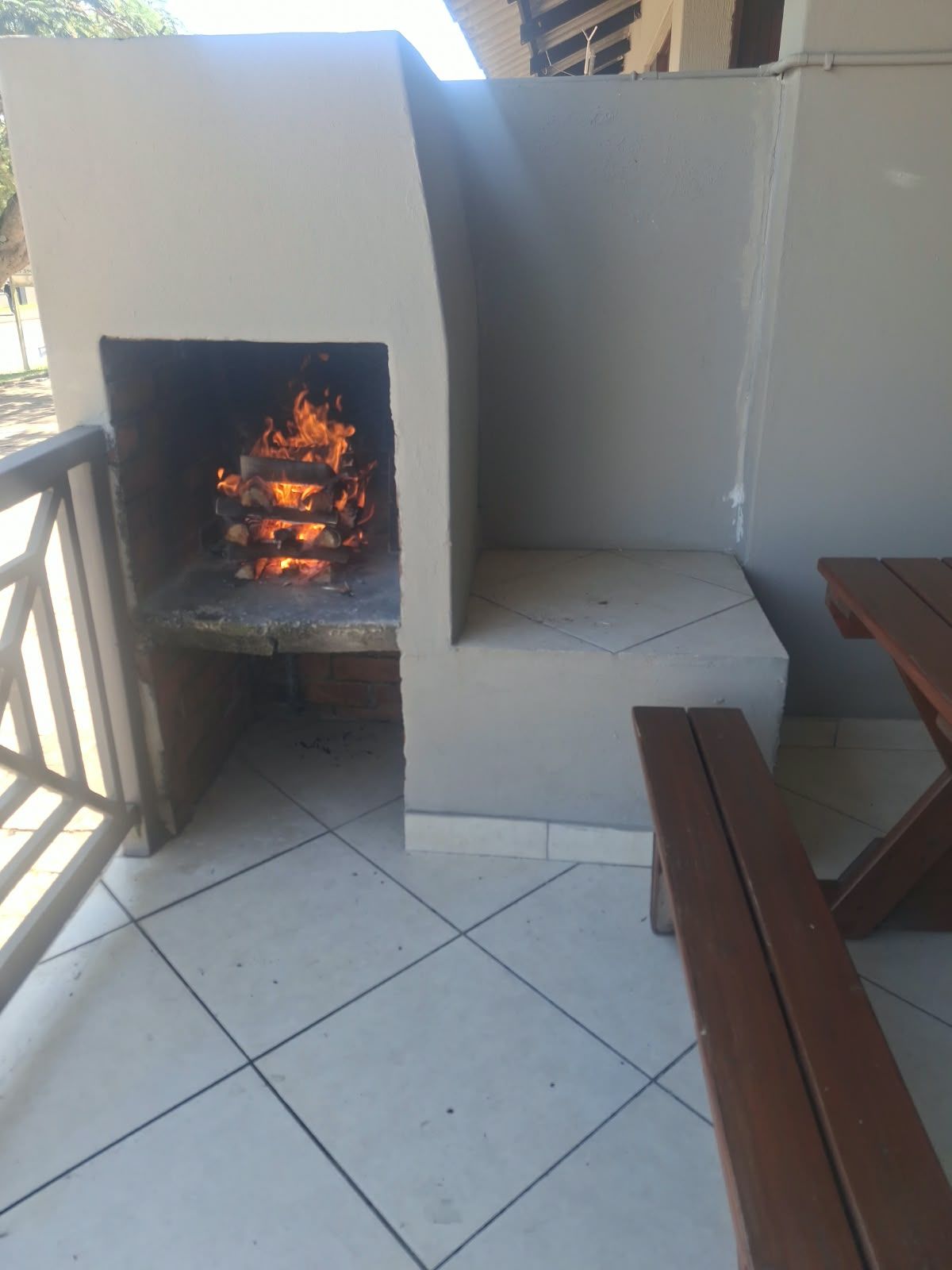 An outdoor barbecue area with a tiled floor and wooden benches.