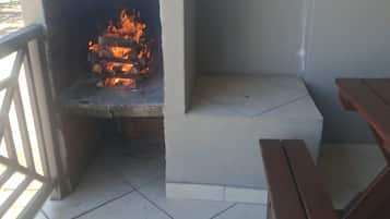 An outdoor barbecue area with a tiled floor and wooden benches.