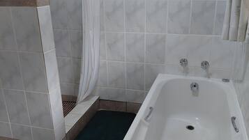Casa de banho com banheira, cortina de chuveiro e porta-toalhas.