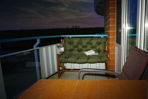 A balcony with a chair and table, a brick wall, and a view of the horizon. - Holiday apartment with 2 bedrooms (Schillig)
