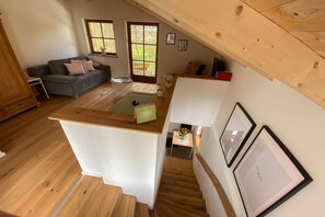 A compact living space with a kitchenette, a dining area, and a staircase leading to an upper level. - Holiday apartment with 1 bedroom (Schönau am Königssee)