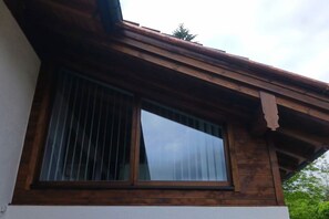 Een gebouw met een houten gevel en een raam met verticale zonwering.