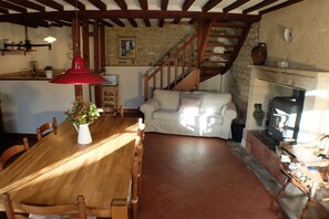 A dining area with a wooden table and chairs, a red pendant light, and a vase with flowers. - Holiday apartment with 2 bedrooms (Ste. Honorine des Pertes)