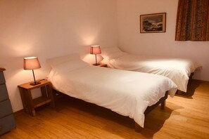A bedroom with two beds, a nightstand with a lamp, a dresser, and a framed picture on the wall.