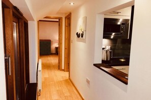 A hallway leading to a kitchen with a microwave and a kettle.