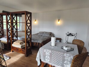 A room with a wooden four-poster bed, two single beds, a table with a lace tablecloth, and a chair with a woven backrest. - Vrbo Property (Cartaxo)