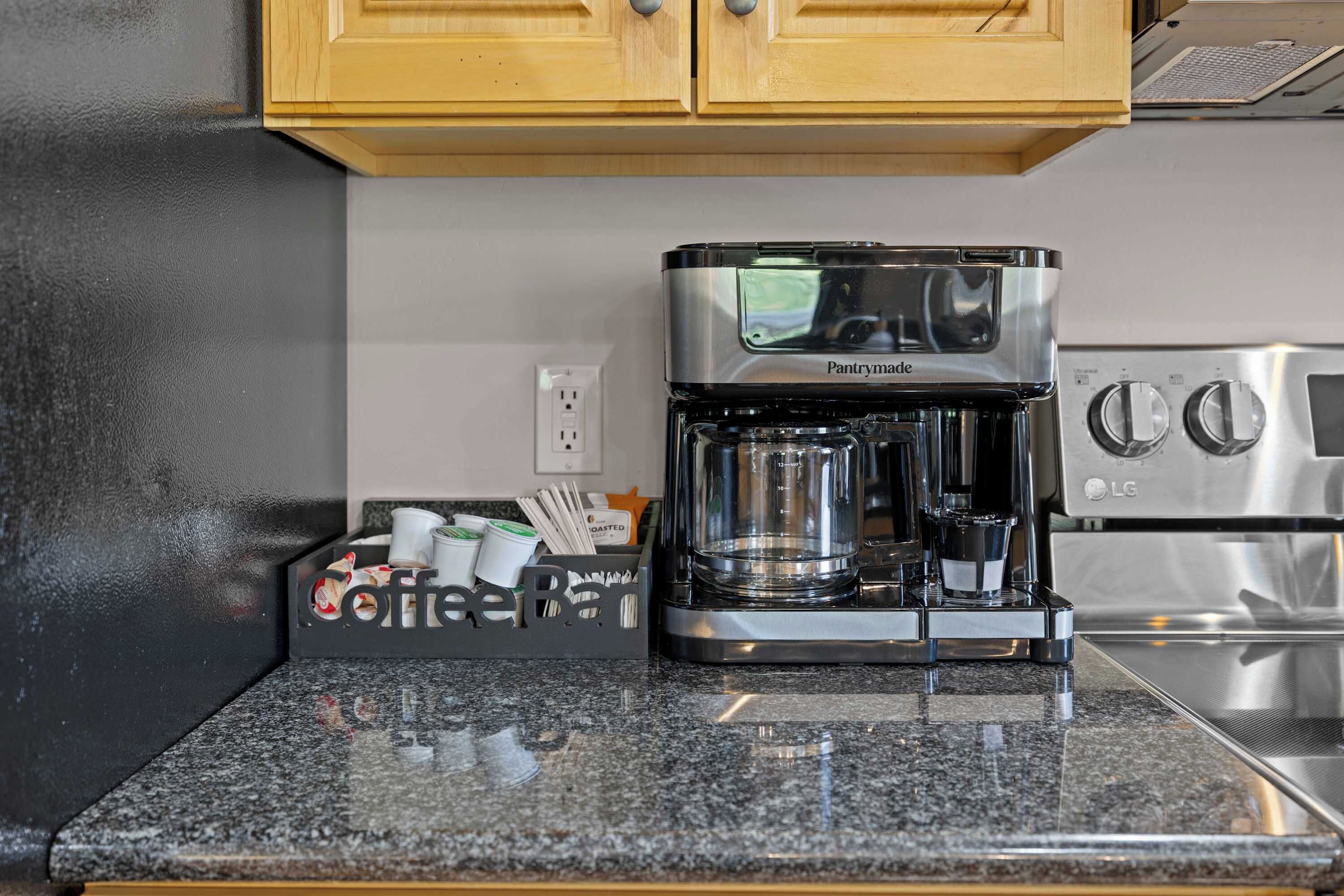 A kitchen with a coffee maker, a coffee bean dispenser, and a stainless steel refrigerator.