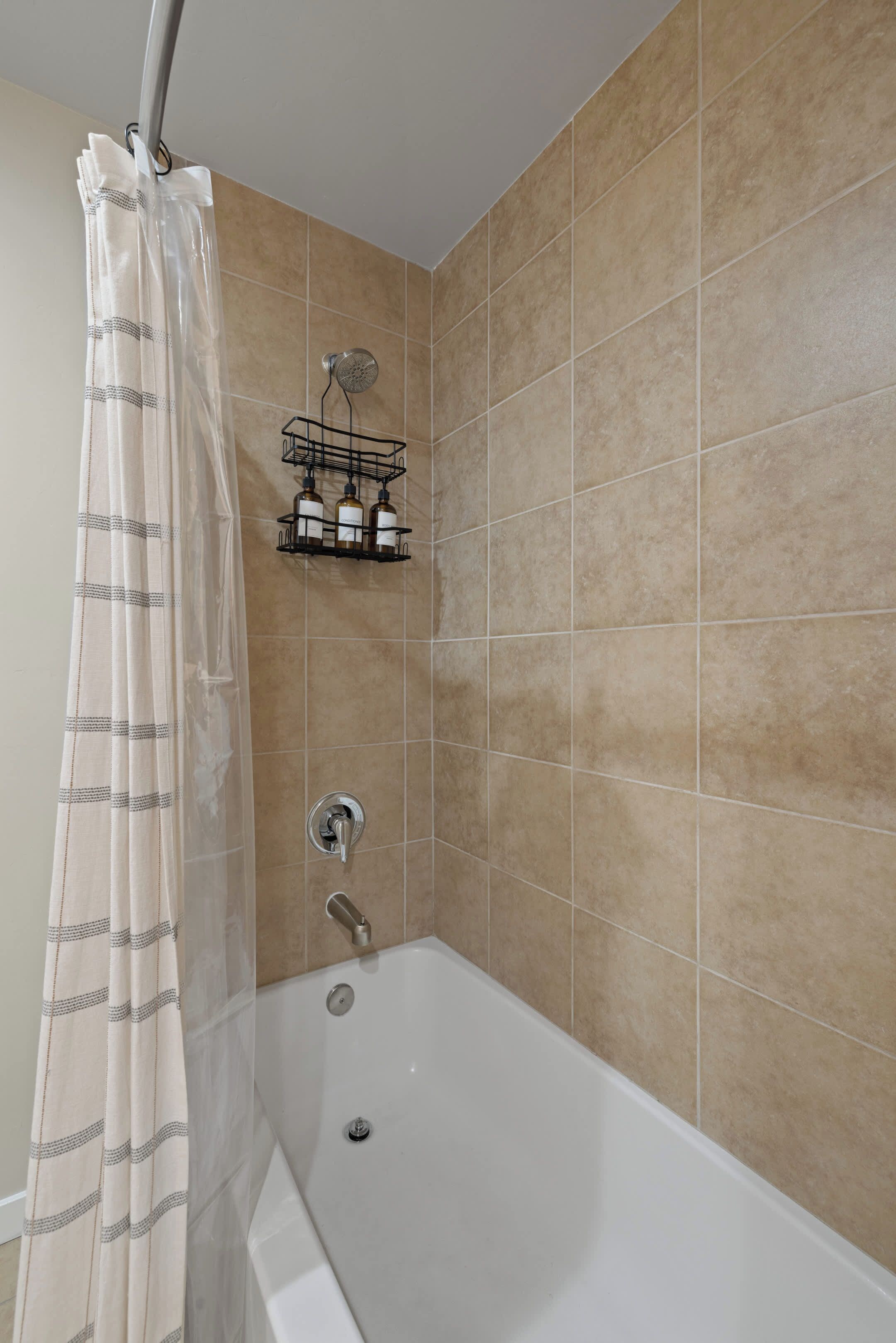 A bathroom with a bathtub, a shower, and a towel rack with bottles.