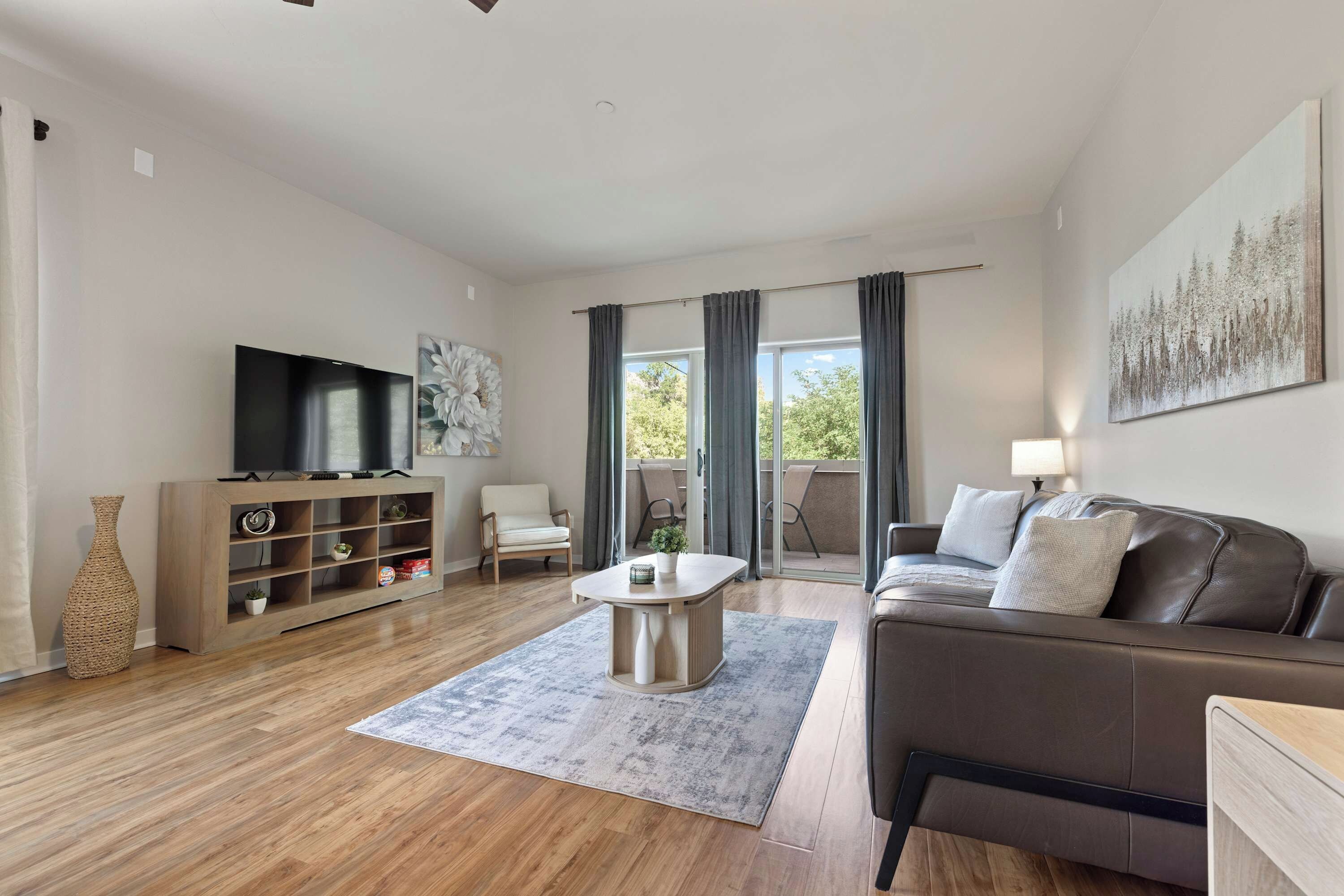A modern living room with a flat-screen TV, a sofa, a coffee table, and a bookshelf.