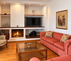 A living room with a fireplace, a television, a sofa, and a coffee table. - Nini's Maison - Terrace Living Above Kalamata City (Kalamata)