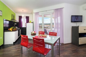 A modern kitchen with a dining area, a TV, and a balcony with a view. - A1 - Modern apartment with big garden and terrace with sea view, 80m from beach (Vinišće)