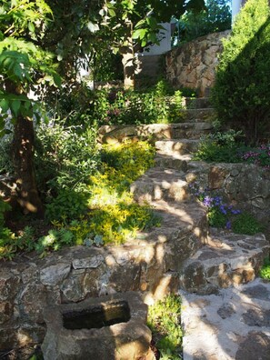 A stone staircase surrounded by lush greenery and flowering plants. - A1 - Modern apartment with big garden and terrace with sea view, 80m from beach (Vinišće)