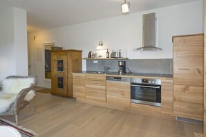 A modern kitchen with wooden cabinets, a built-in oven, and a coffee maker. - Mayrhof West Apartment (Mittenwald)