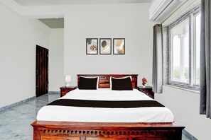 A hotel room with a large bed, a nightstand, a lamp, and a window with curtains. - Hotel College And Institute Technology (Jalsu)