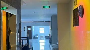 Un couloir d’hôtel avec un sol en marbre, un comptoir d’accueil et un espace détente.