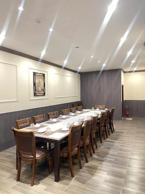 Un salón de conferencias con una larga mesa, sillas y un cuadro en la pared.