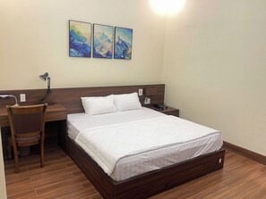 Une chambre d’hôtel comprenant un lit, un bureau, une chaise, une table de chevet et une œuvre d’art accrochée au mur.