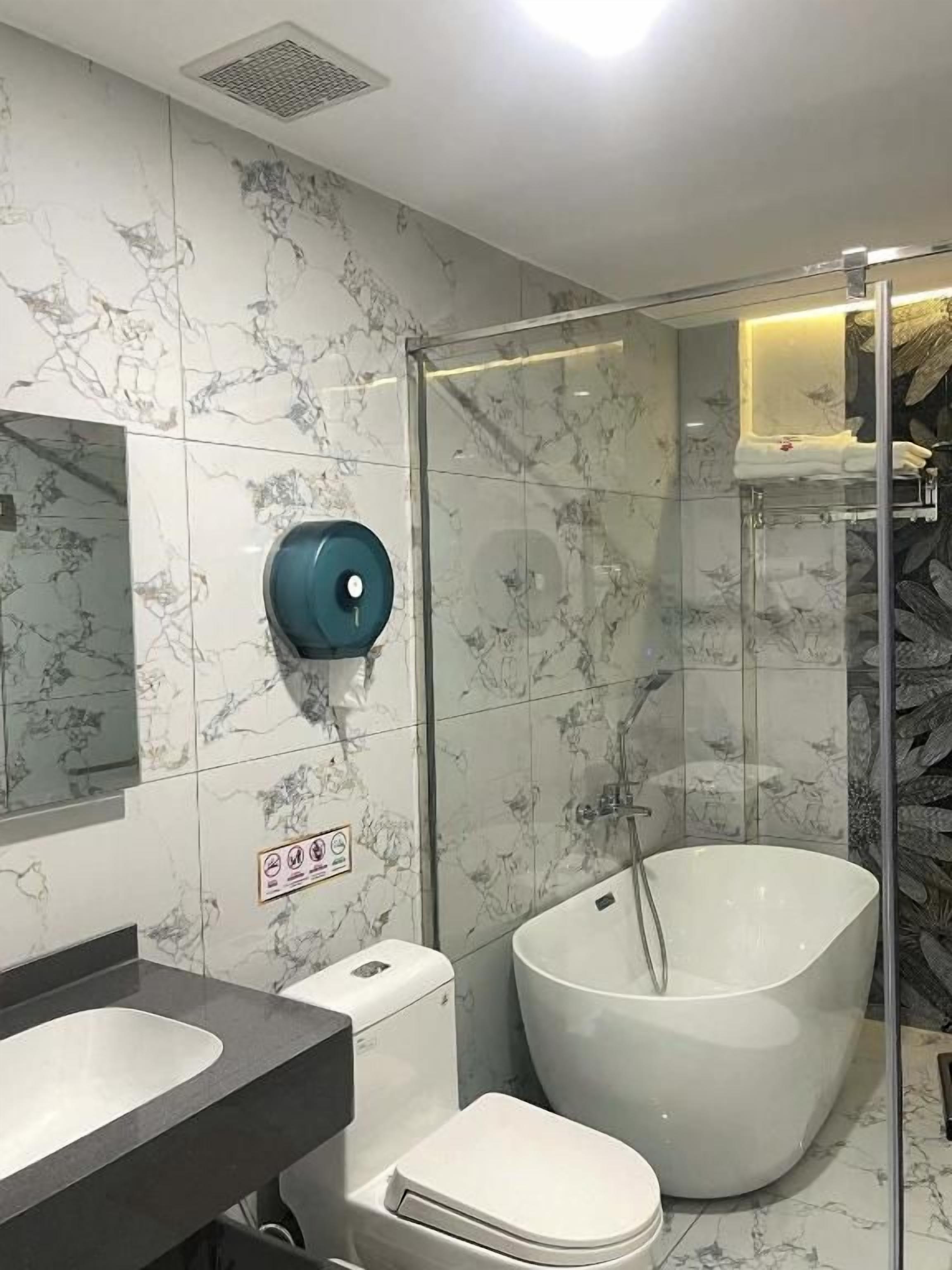 A bathroom with a glass-enclosed shower, a freestanding bathtub, and a toilet.
