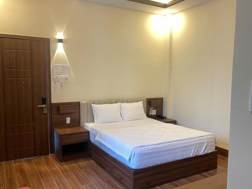 A bedroom with a wooden bed, a nightstand, and a wall-mounted light fixture.