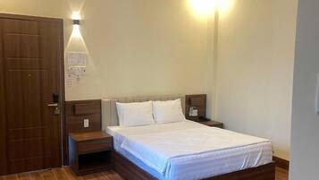 A bedroom with a wooden bed, a nightstand, and a wall-mounted light fixture.