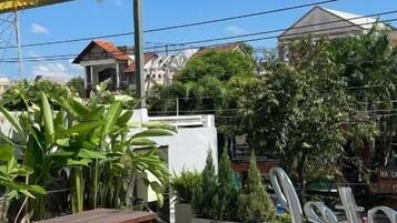 Eine Terrasse im Freien mit Holztischen und -bänken, umgeben von Topfpflanzen und einem gemusterten Boden.