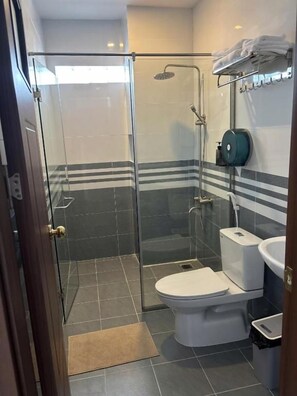 Un baño moderno con ducha de vidrio, inodoro y lavamanos.