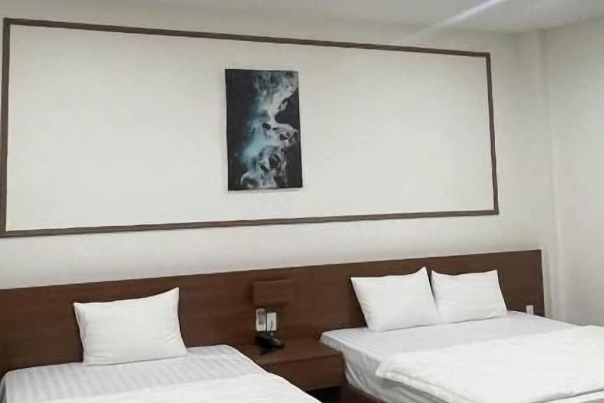 Habitación de hotel con dos camas, una mesita de noche y un diseño de techo moderno.