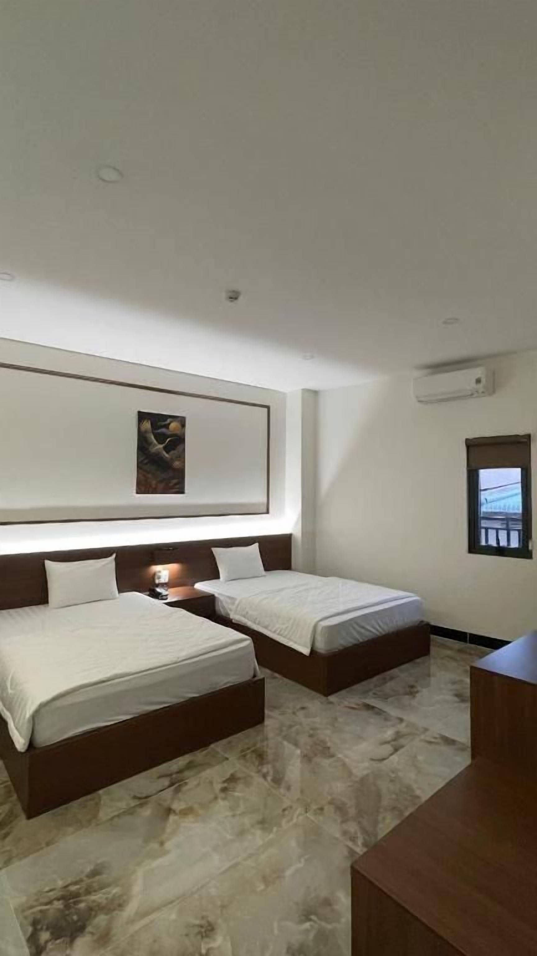 Habitació d'hotel amb dos llits, un sòl de marbre, un quadre a la paret i una finestra amb vista.