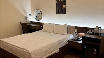 Une chambre d’hôtel comprenant un lit, une table de chevet, une lampe et une œuvre d’art accrochée au mur.