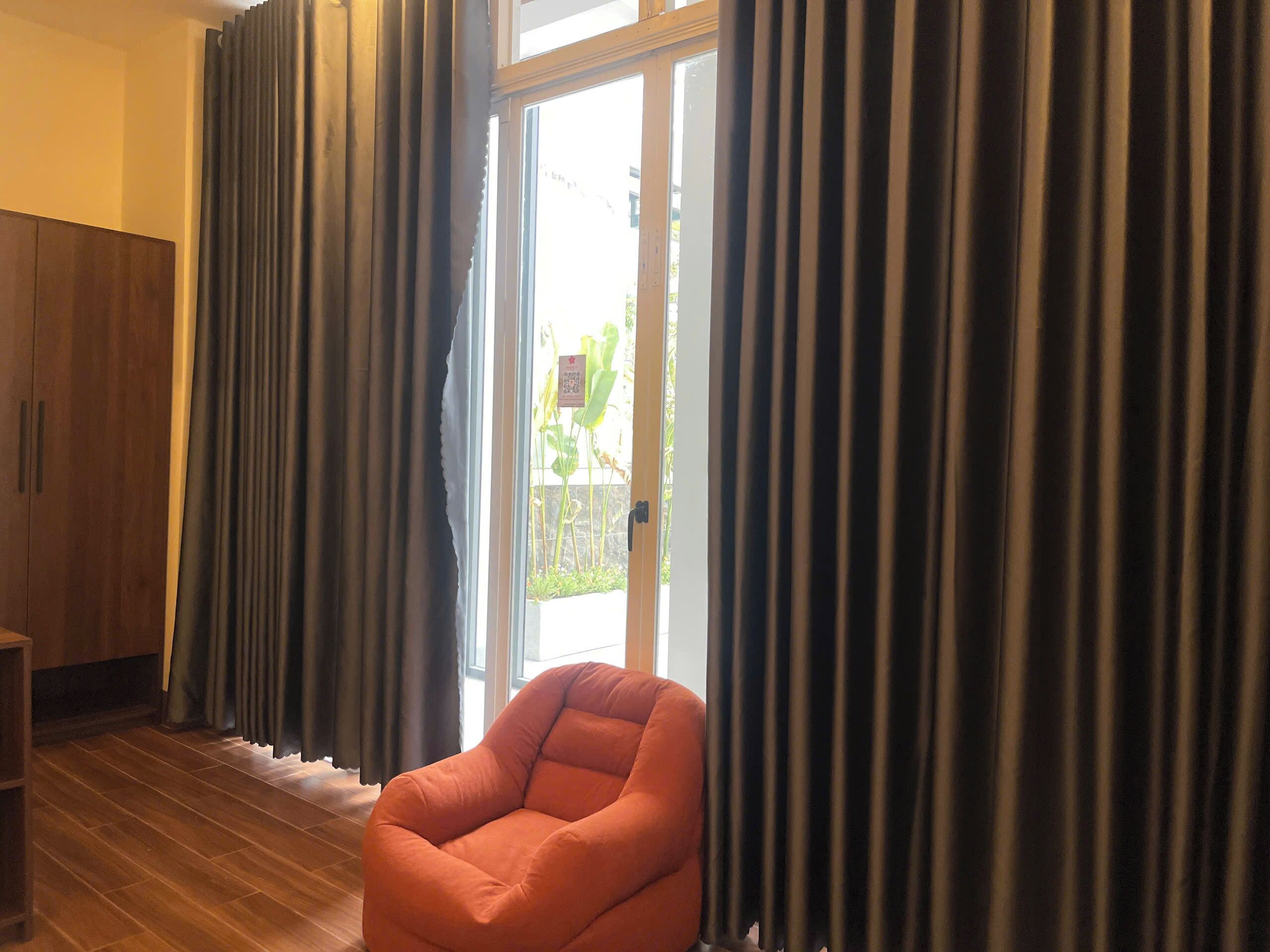 A room with a wooden floor, a brown armchair, and a sliding glass door leading to an outdoor area.
