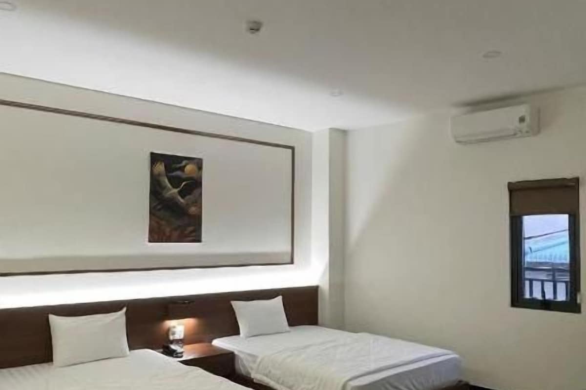 Habitación de hotel con dos camas, piso de mármol, un cuadro en la pared y una ventana con vistas.