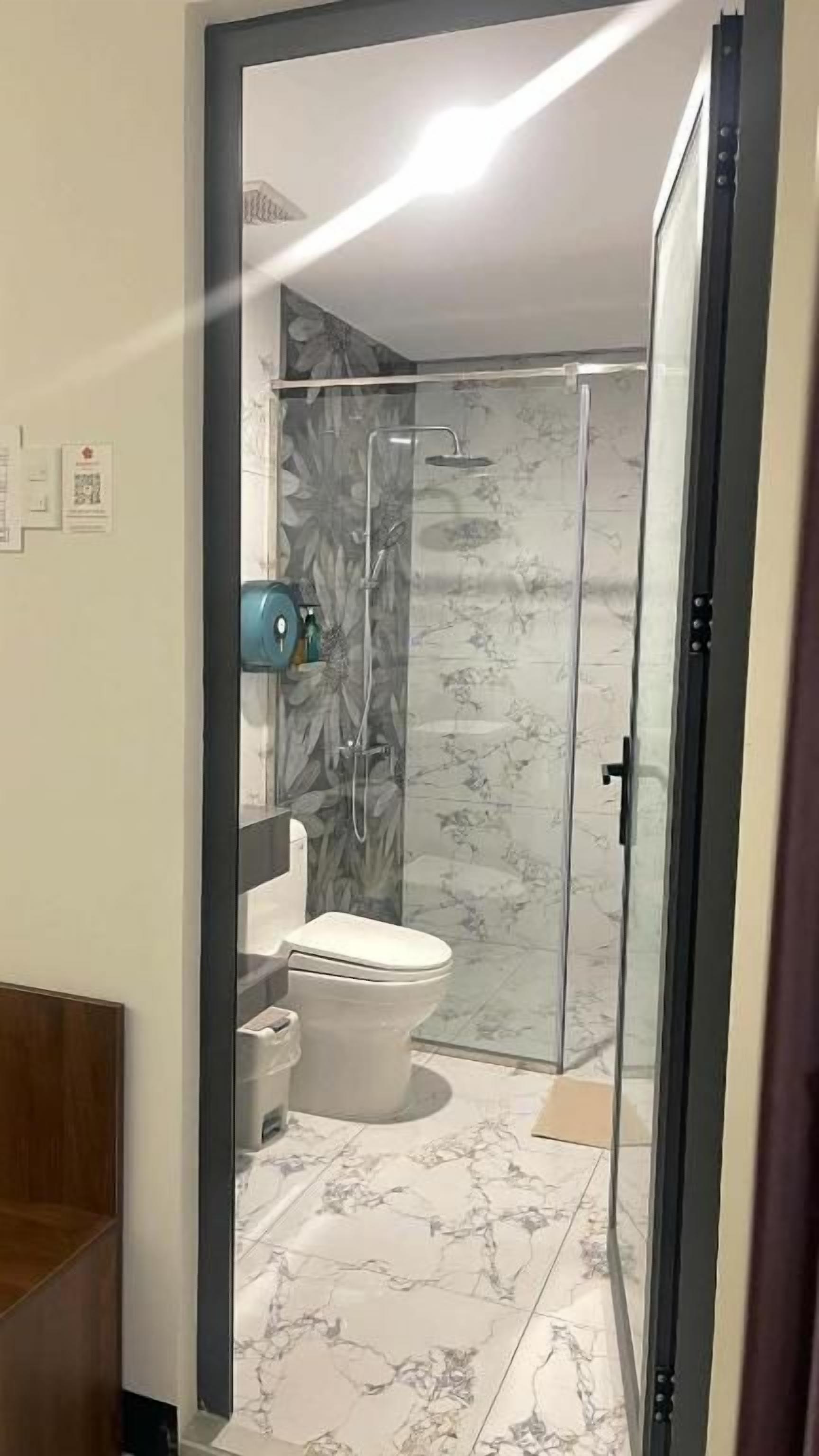 Un baño con cabina de ducha de vidrio, inodoro y lavabo.