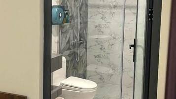 Un baño con cabina de ducha de vidrio, inodoro y lavabo.