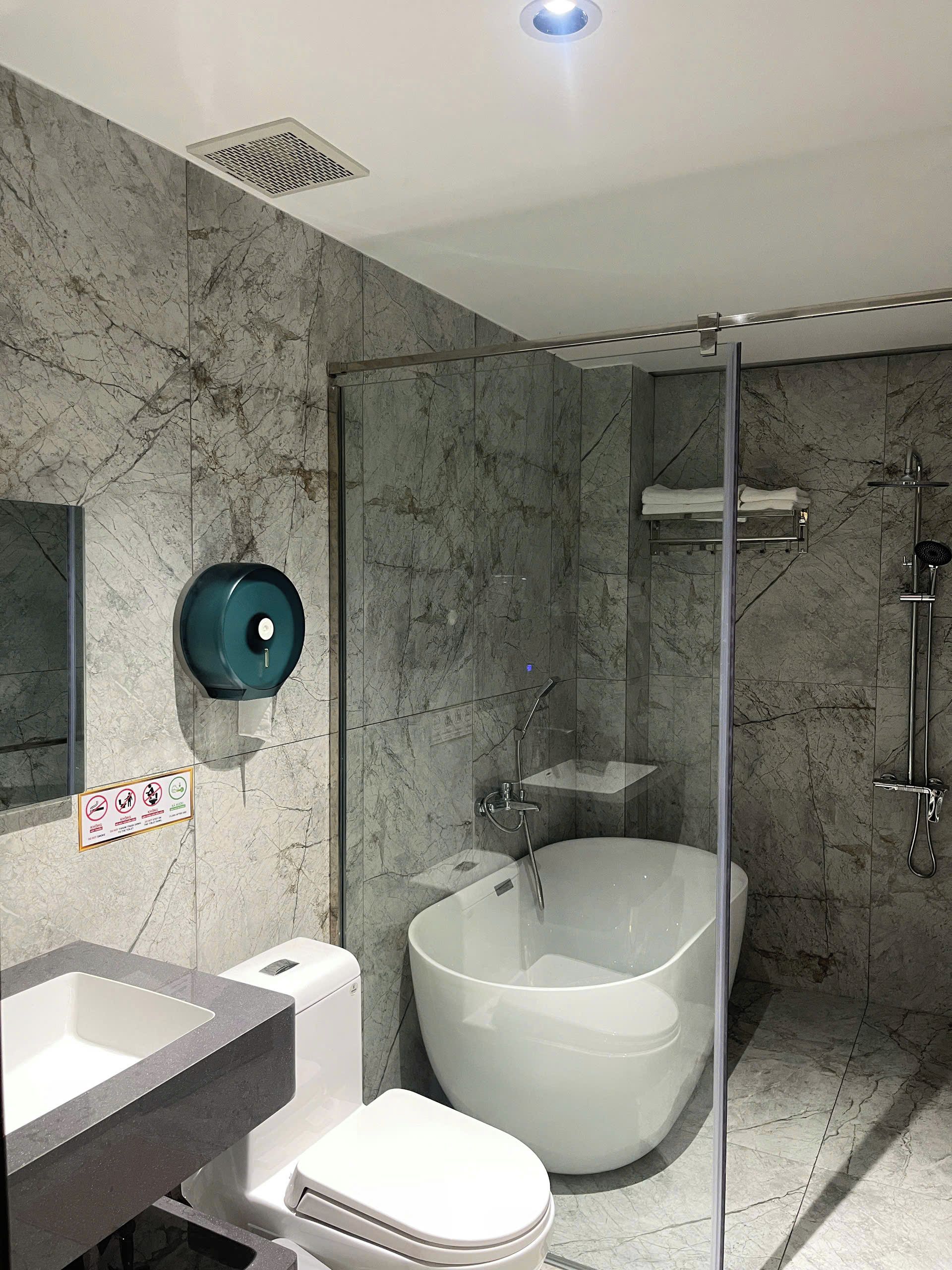 A modern bathroom with a glass-enclosed shower, a freestanding bathtub, and a toilet.