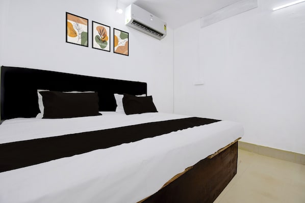 A bed with a black headboard, white bedding, and two black pillows. There are three framed pictures on the wall above the bed. - Hotel Formerly Family Guest House (Patna)