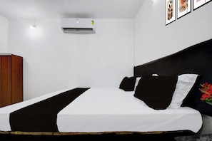 A hotel room with a bed, a wardrobe, and an air conditioning unit on the wall. - Hotel Formerly Family Guest House (Patna)