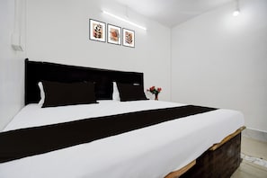 A bed with a black headboard, white bedding, and a black accent strip. There are three framed pictures on the wall above the bed. - Hotel Formerly Family Guest House (Patna)