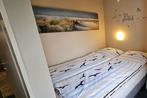 Ein Schlafzimmer mit einem Bett, einem Wandbild und einer Wandleuchte.